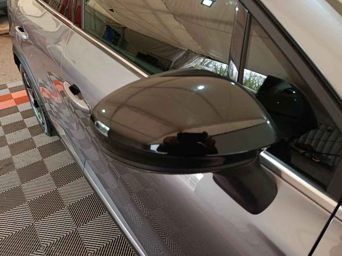 Rétroviseur noir brillant en gros plan sur le côté gauche d'une Renault SYMBIOZ gris métallisé, vue partielle latérale.