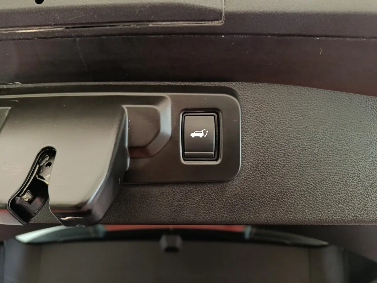 Bouton d'ouverture électrique du coffre sur panneau intérieur noir, détail du Renault SYMBIOZ hybride 2025.