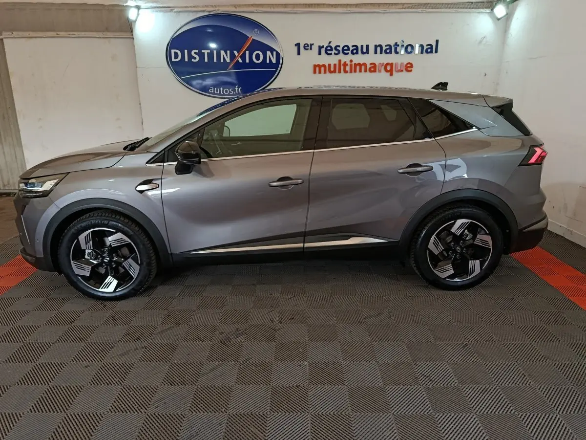 Profil droit du Renault SYMBIOZ 2025 gris métallisé avec jantes noires et détails modernes en intérieur showroom.