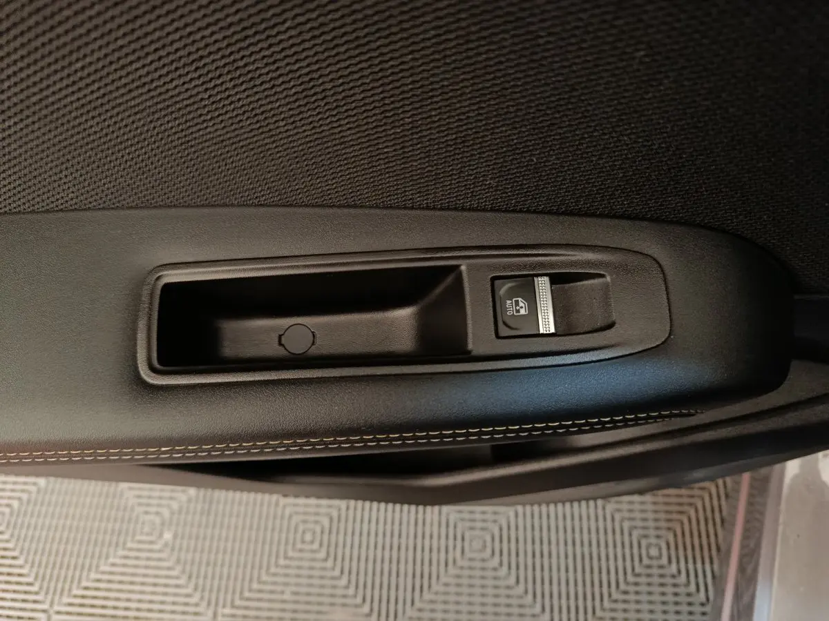 Gros plan sur la commande de lève-vitre côté porte intérieure d'une Renault SYMBIOZ 2025, finition noire avec surpiqûres.