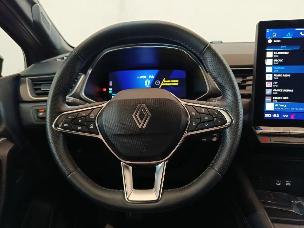 Vue frontale du volant noir perforé de la Renault SYMBIOZ 2025 avec tableau de bord numérique et écran tactile latéral.