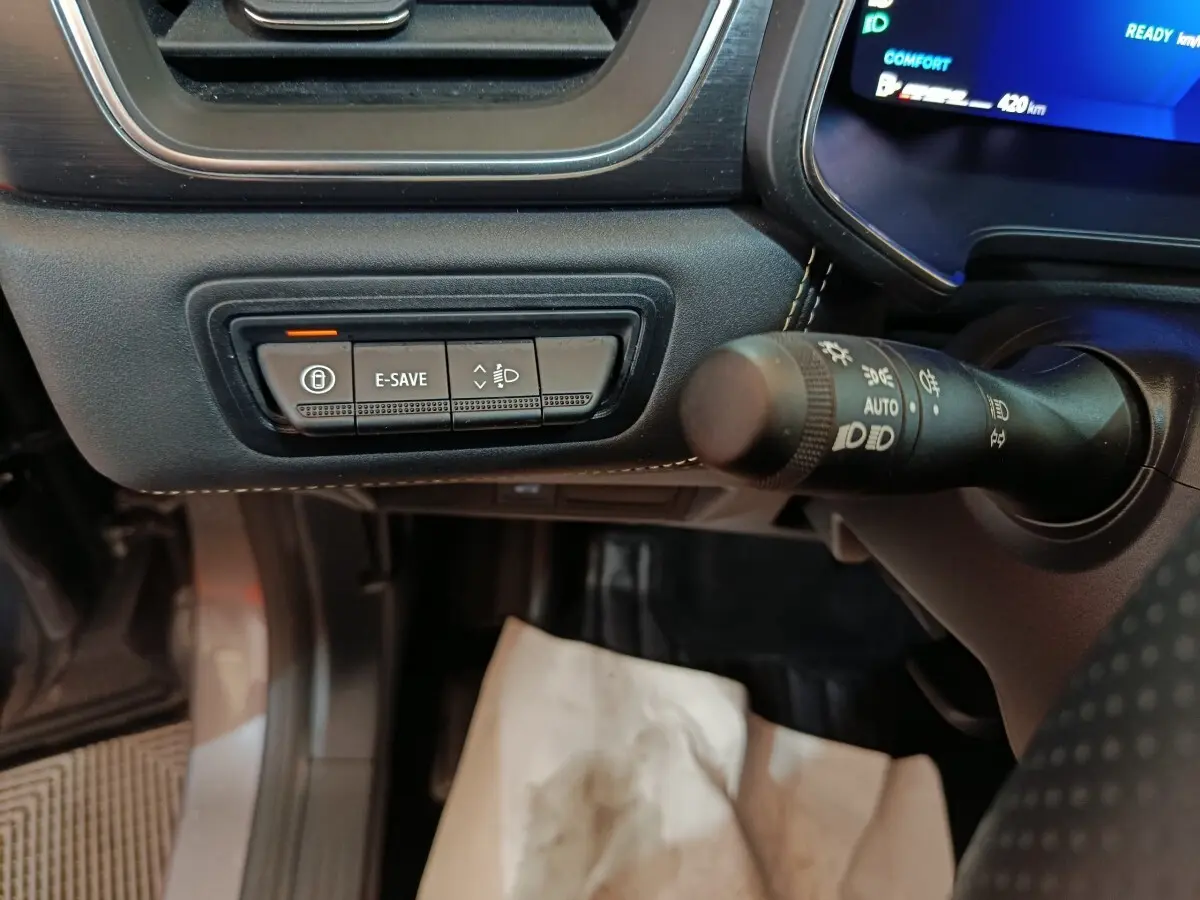 Gros plan sur les commandes noires du tableau de bord côté gauche du Renault Symbioz 2025 avec éclairage bleu à l'écran.