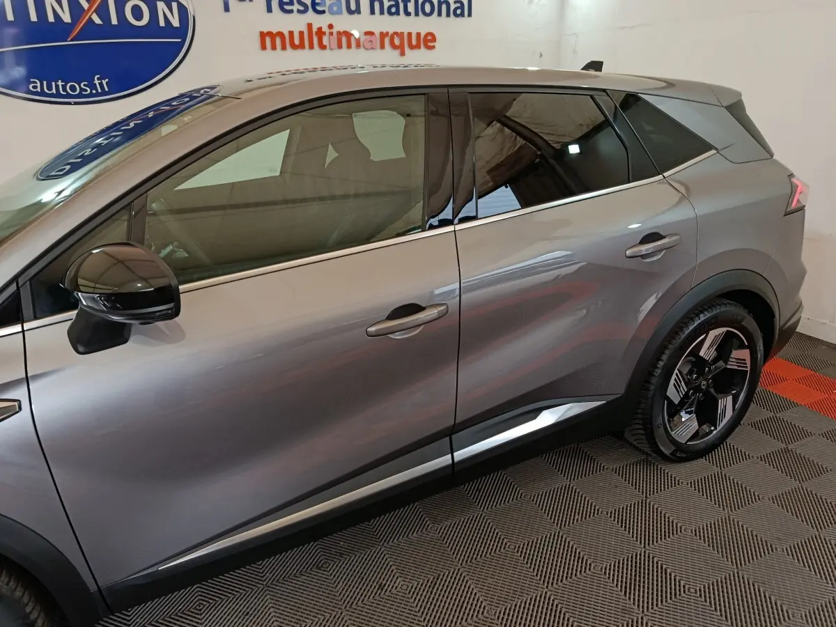 Vue latérale droite du Renault SYMBIOZ gris métallisé avec jantes noires et toit contrasté dans un showroom.