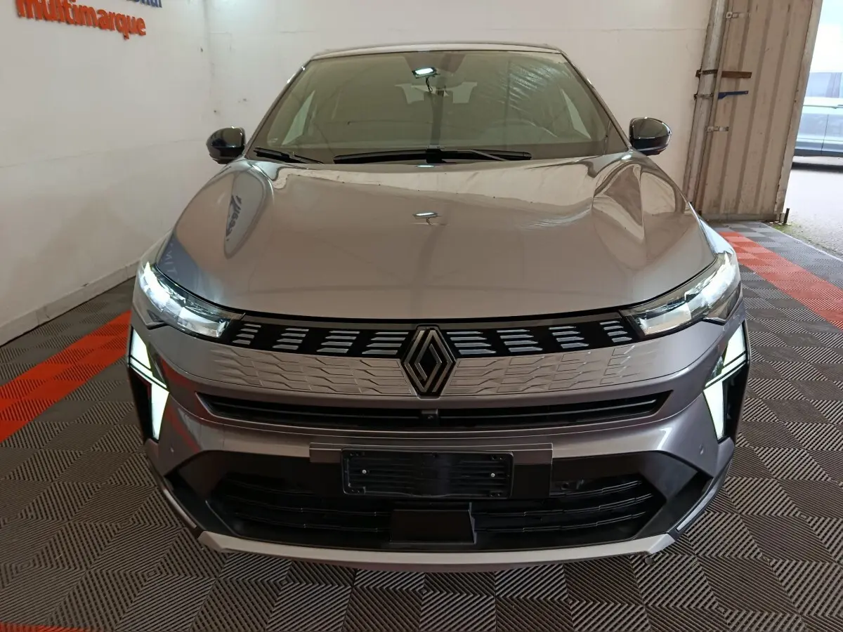 Vue frontale d'une Renault SYMBIOZ gris clair avec feux LED allumés et calandre au design moderne.