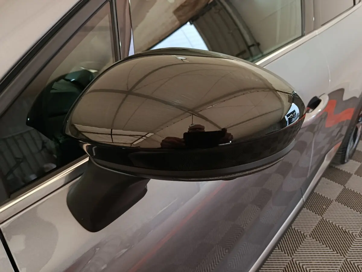 Gros plan sur le rétroviseur droit noir brillant du Renault Symbioz 2025, avec carrosserie gris clair visible en arrière-plan.