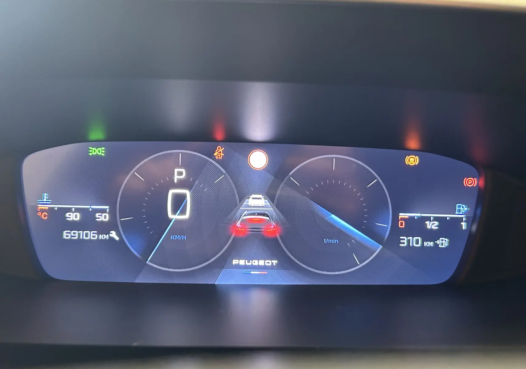 Tableau de bord numérique de Peugeot 308 gris, affichant la vitesse à 0 km/h et une autonomie de 310 km.