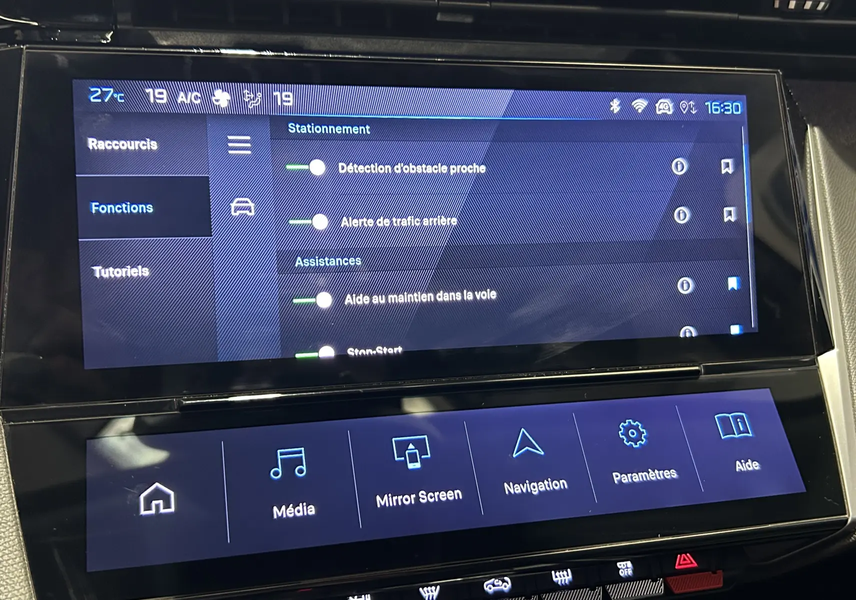 Écran tactile central de la Peugeot 308 gris, affichant les options d'assistance à la conduite et navigation.