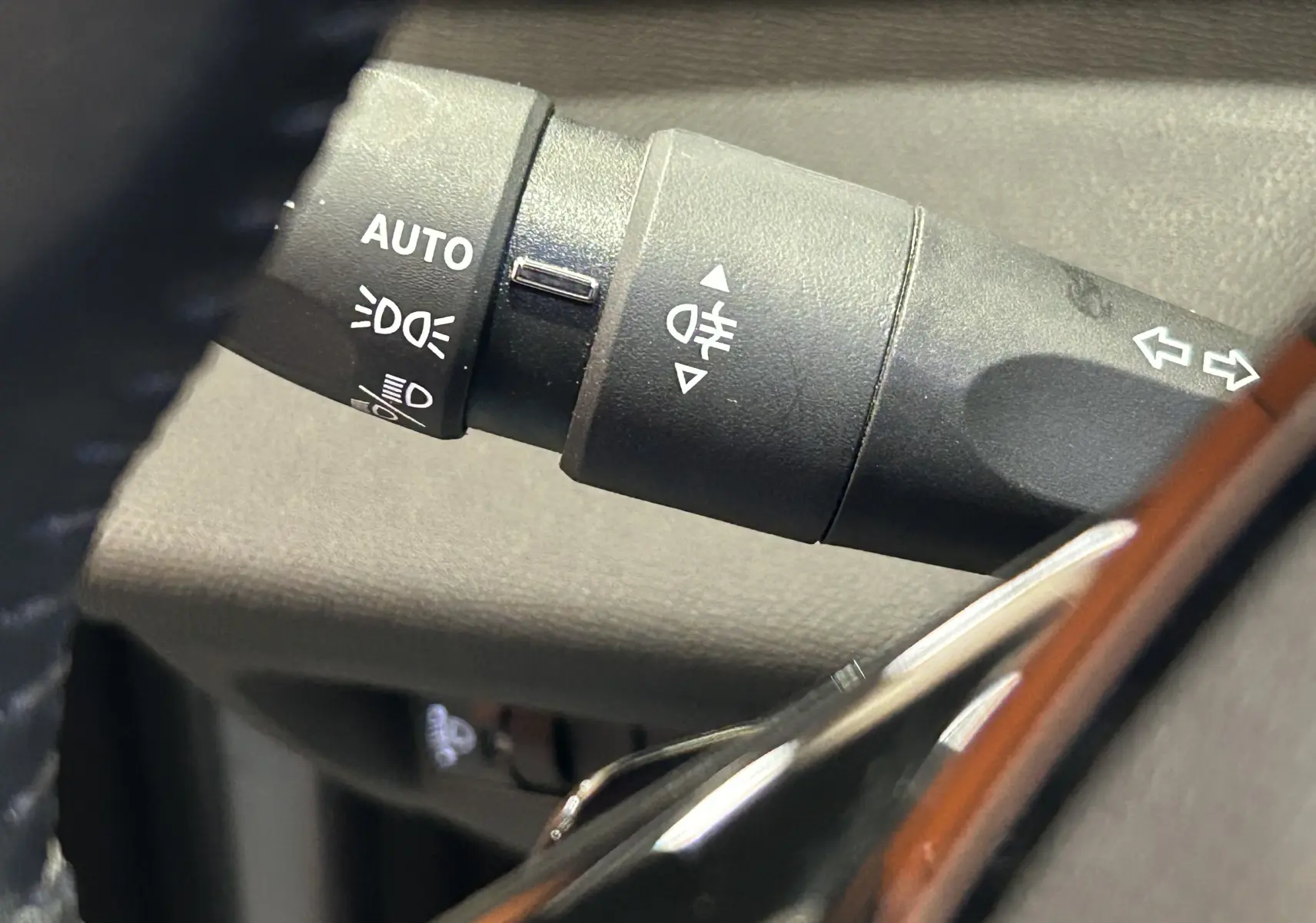 Gros plan sur la commande des feux et clignotants à gauche du volant dans l’habitacle d’une Peugeot 308 gris 2022.