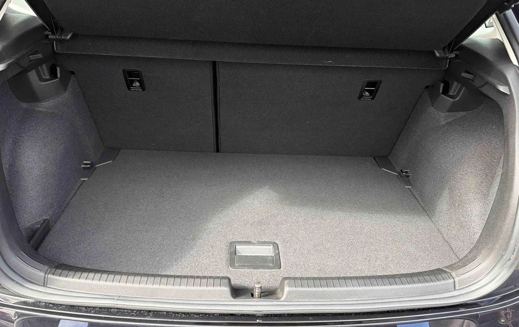 Coffre ouvert vu de l'arrière d'une Volkswagen Polo noire, montrant un espace de chargement propre et vide.