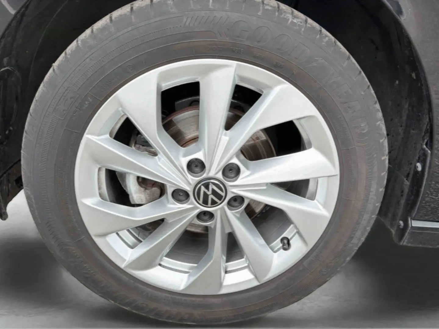 Gros plan sur la jante alliage 16'' Palermo argentée avec logo Volkswagen, montée sur pneu Goodyear d'une Polo noire.