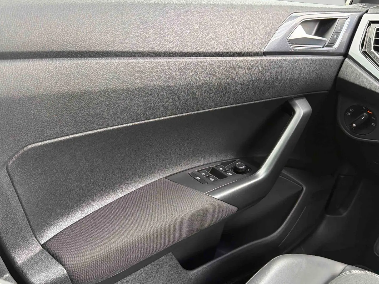 Vue intérieure côté conducteur de la porte noire de la Volkswagen Polo 2025 avec commandes des vitres et rétroviseurs.