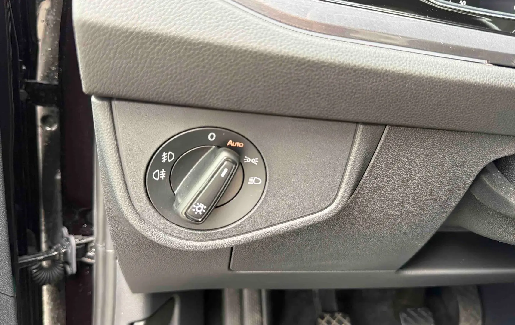 Gros plan sur le bouton de commande des phares à gauche du tableau de bord d'une Volkswagen Polo noire 2025.