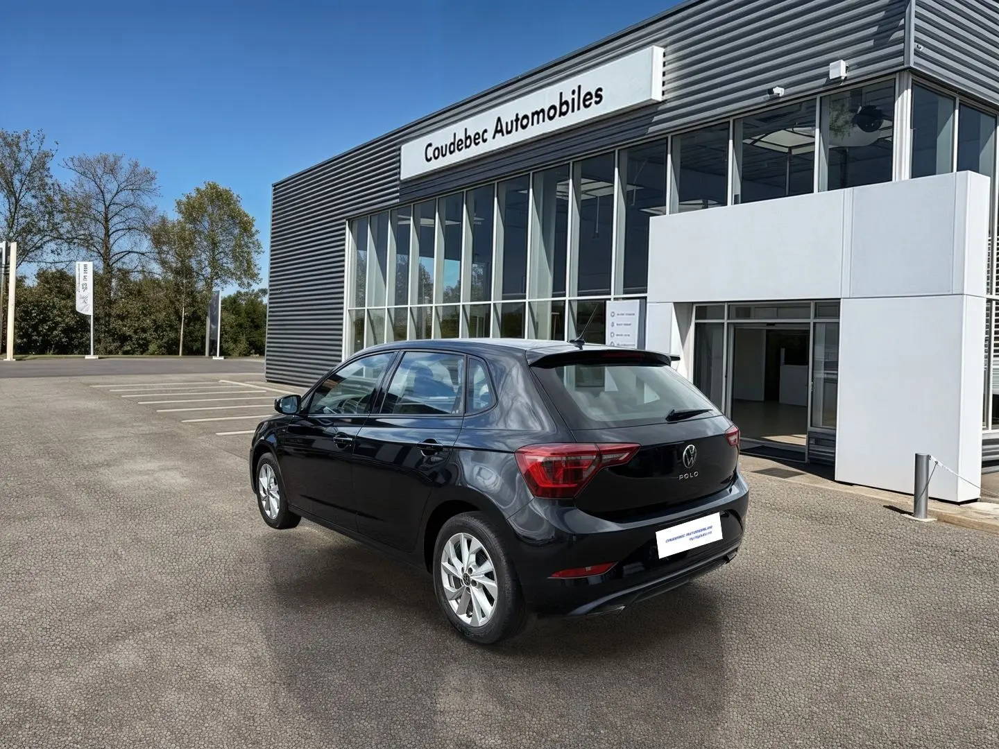 Volkswagen Polo noire vue 3/4 arrière droit, avec jantes alliage 16'' devant un bâtiment moderne.