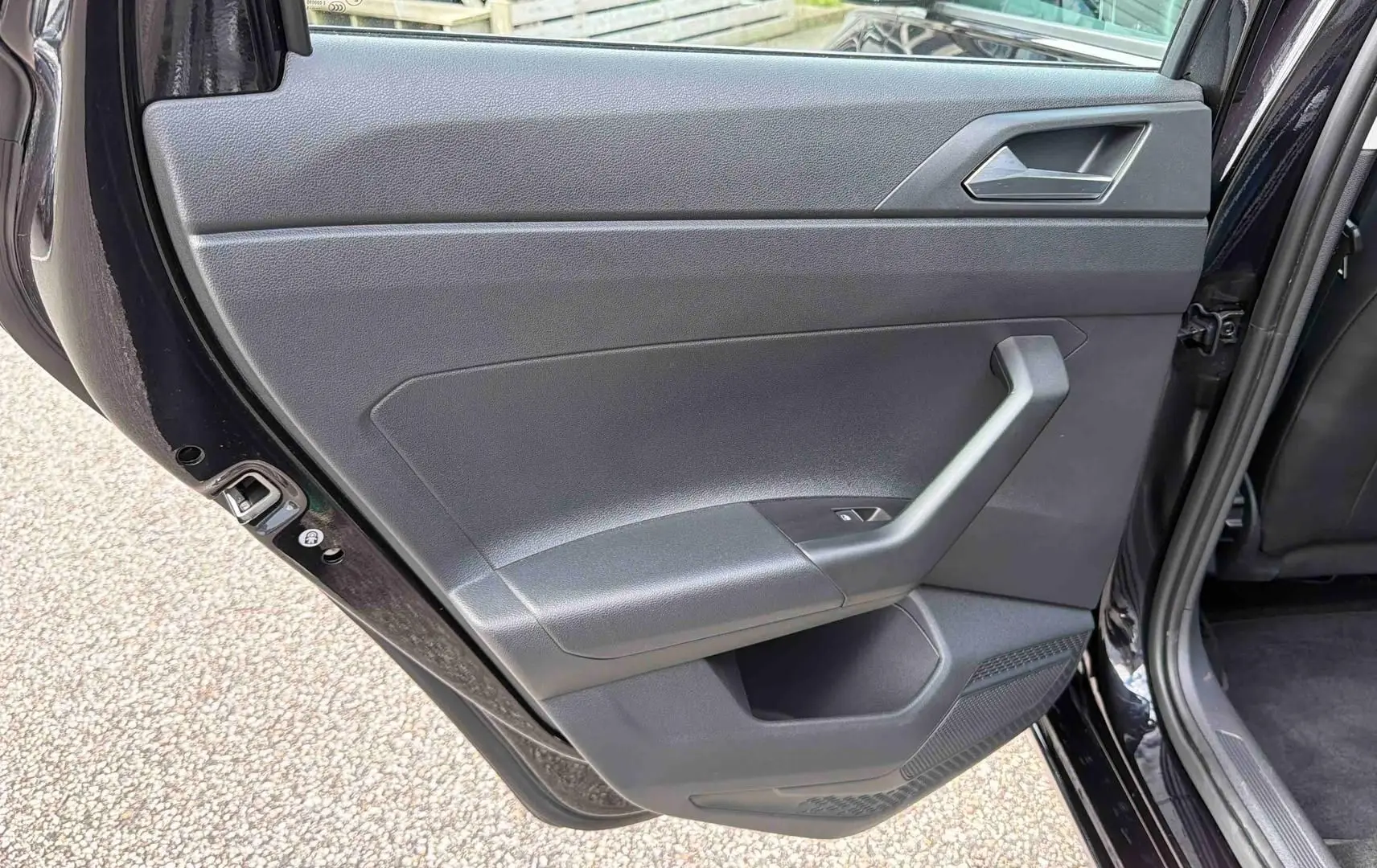 Vue intérieure de la porte arrière gauche noire d’une Volkswagen Polo 2025 avec poignée et commande de vitre.