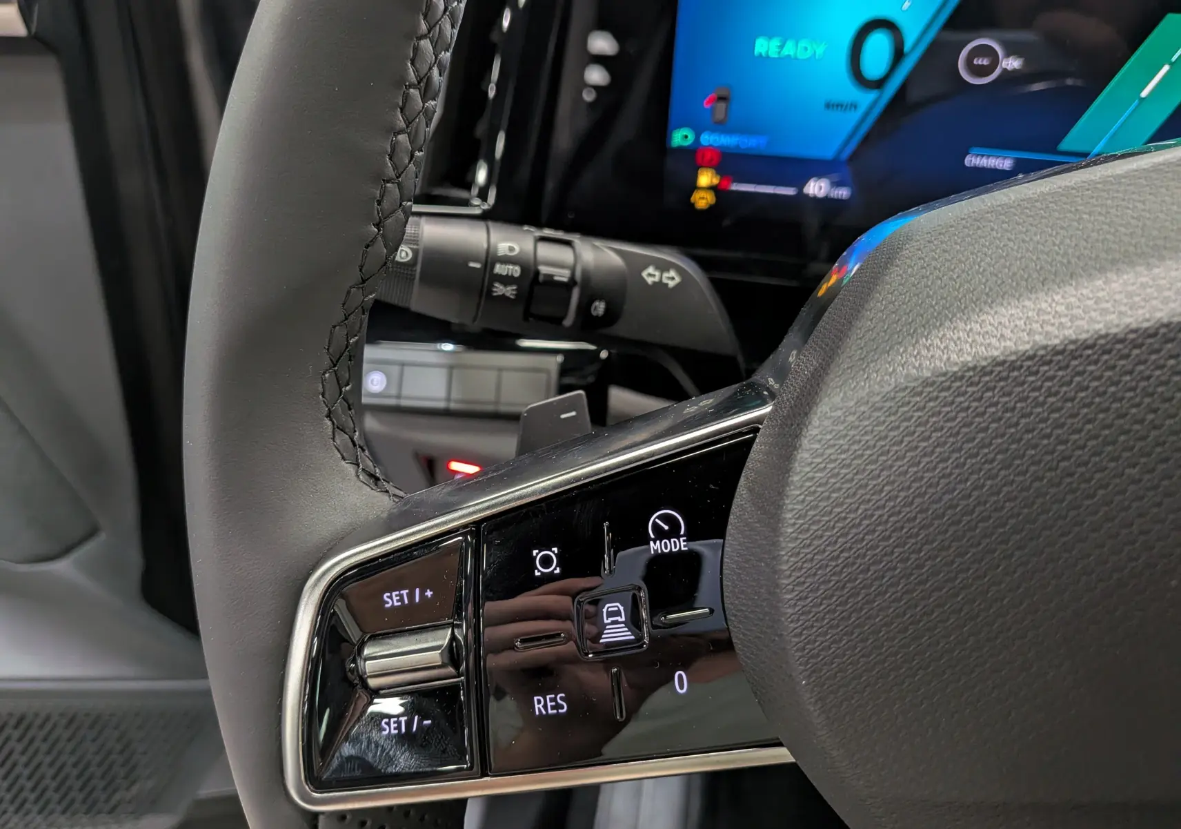 Gros plan sur le volant noir et les commandes tactiles côté gauche du Renault Rafale E-Tech 2026, avec tableau de bord digital bleu en arrière-plan.