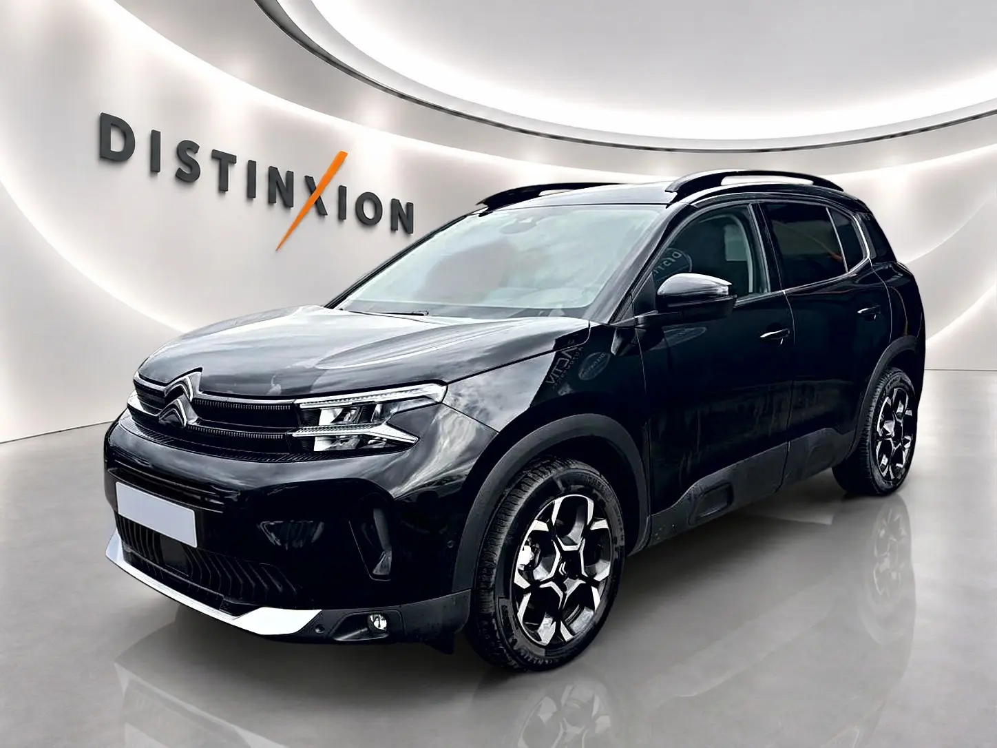 Citroën C5 Aircross noir vue 3/4 avant droit avec jantes alu et barres de toit en showroom.