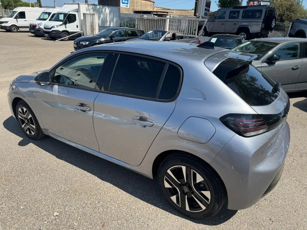 Peugeot 208 Hybrid gris vue 3/4 arrière droit, jantes alliage 16 pouces et feux arrière noirs distinctifs.