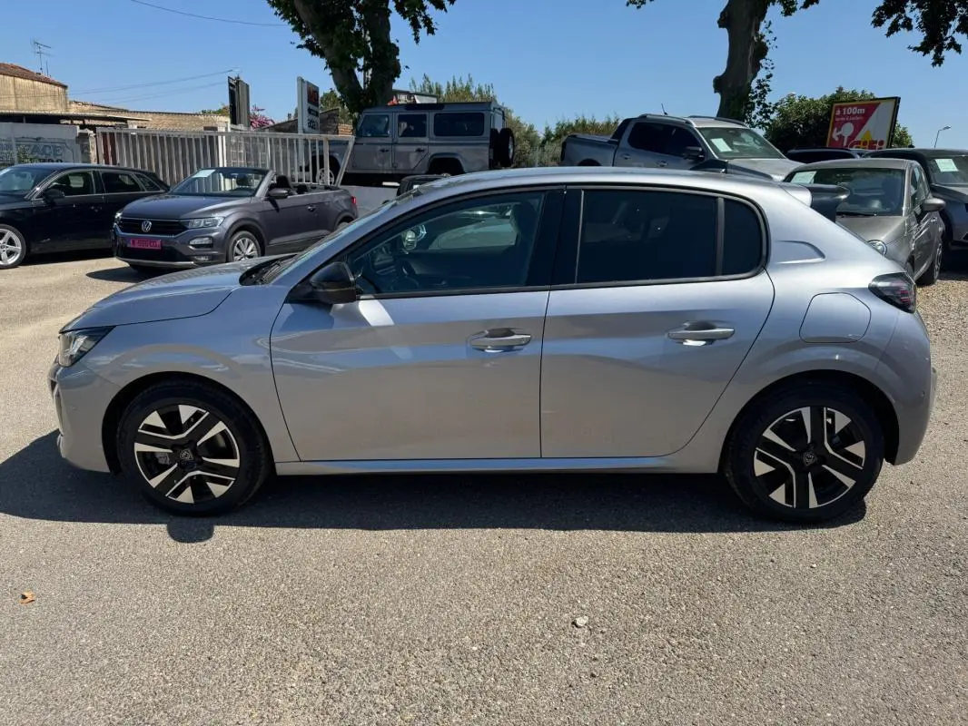 Profil droit d'une Peugeot 208 Hybrid 110 gris 2025 avec jantes alliage 16 pouces et antenne requin.