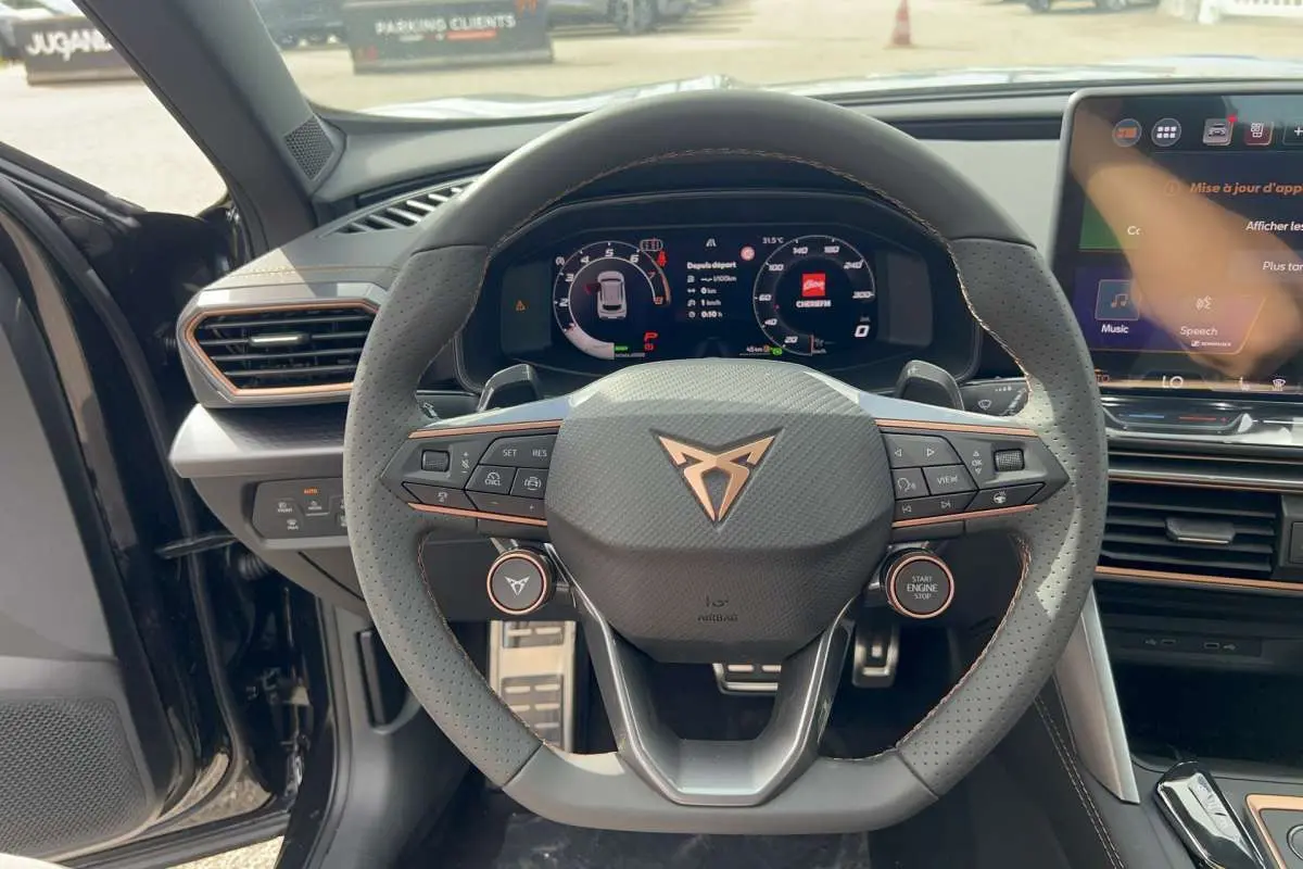 Vue intérieure centrée sur le volant cuir perforé noir minuit du CUPRA Formentor avec tableau de bord digital et écran tactile.