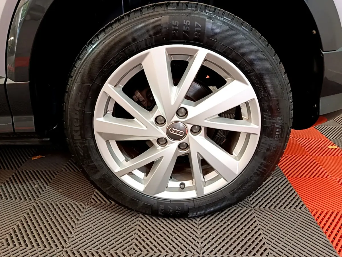 Gros plan sur la roue avant droite d’un Audi Q2 gris clair, mettant en valeur la jante alliage à 5 doubles branches.