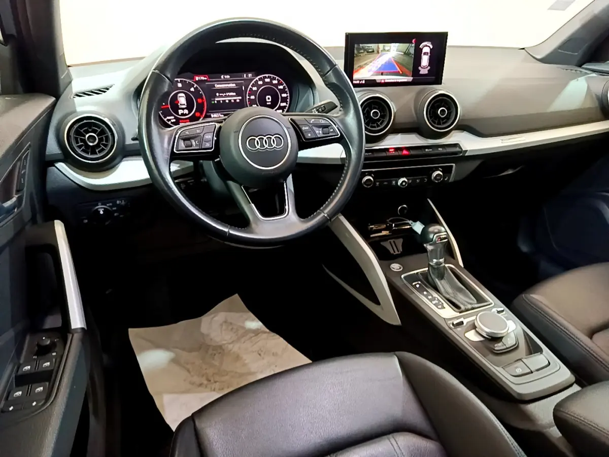 Vue intérieure de l'Audi Q2 35 TDI 150 Design 2020, tableau de bord noir avec écran central et volant cuir multifonctions.