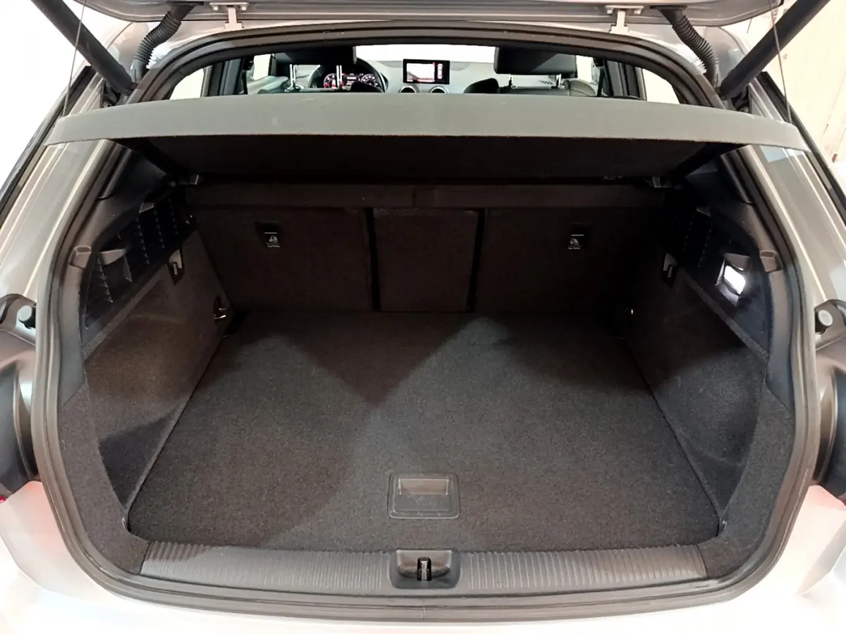 Coffre ouvert d’un Audi Q2 gris clair, vue arrière montrant l’espace de chargement et la tablette de séparation.