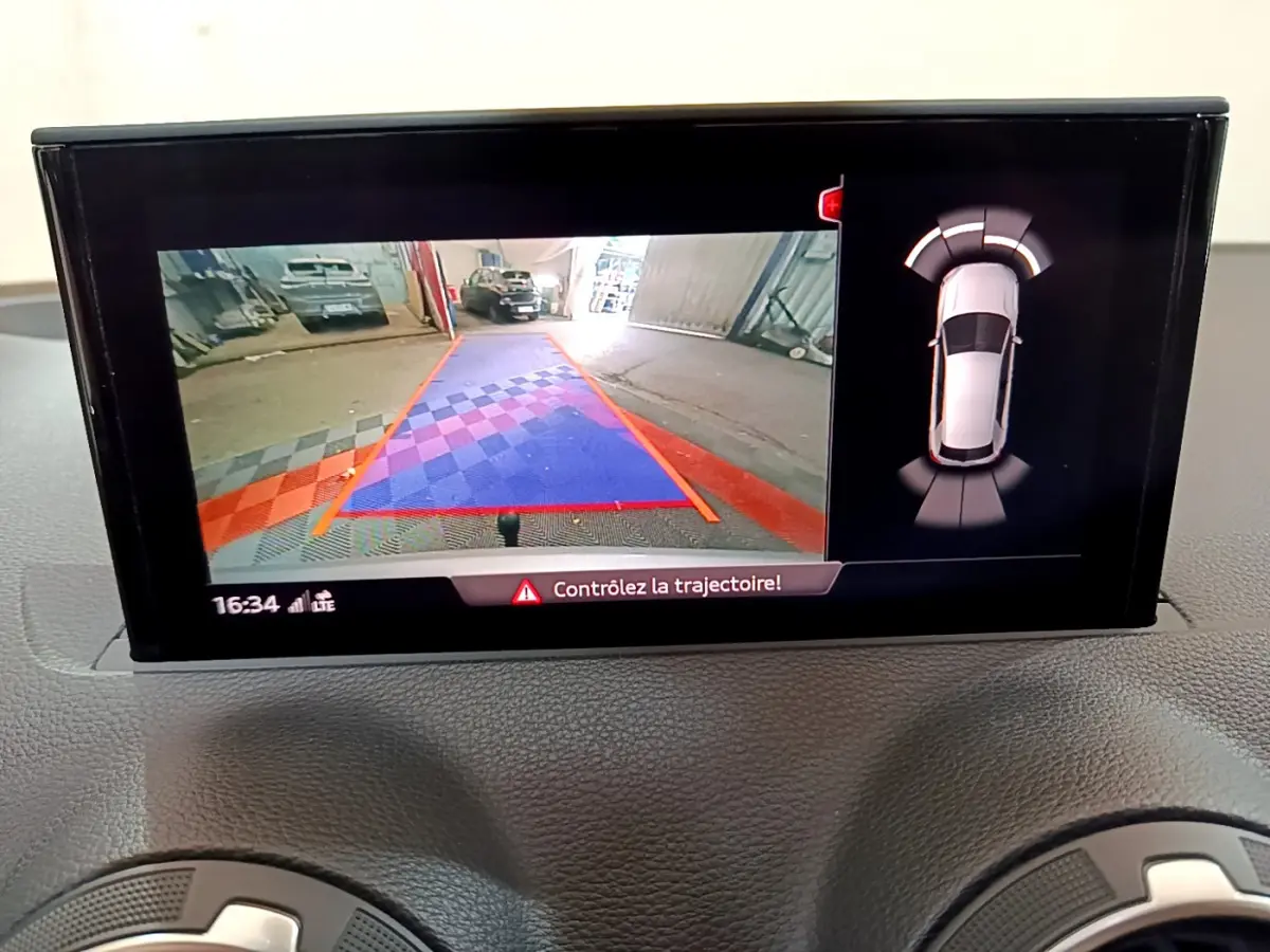 Écran multimédia de l'Audi Q2 35 TDI 150 Design 2020 montrant la caméra de recul et les capteurs de stationnement.