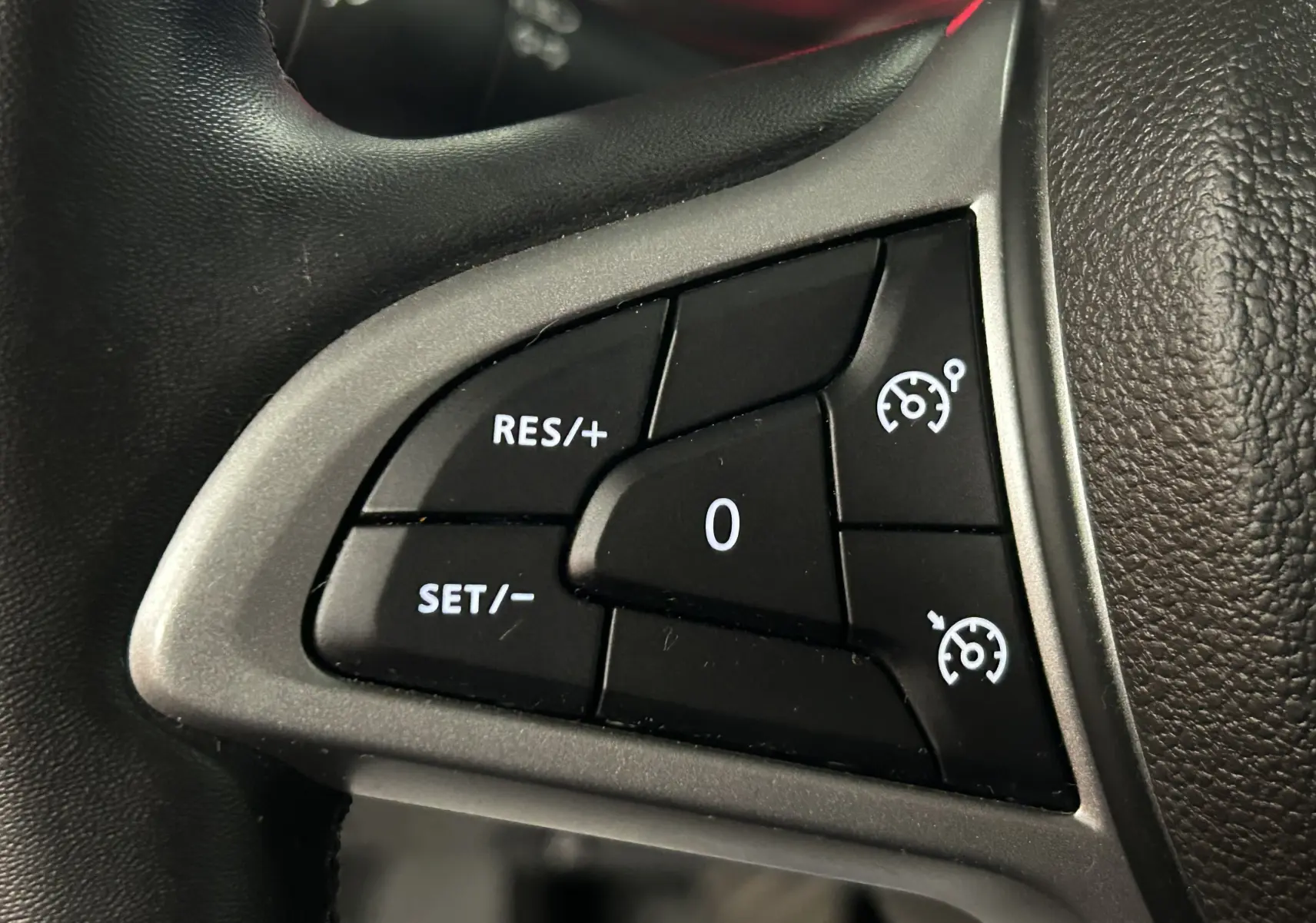 Gros plan sur les commandes de régulateur de vitesse au volant noir du Dacia Duster 2024.