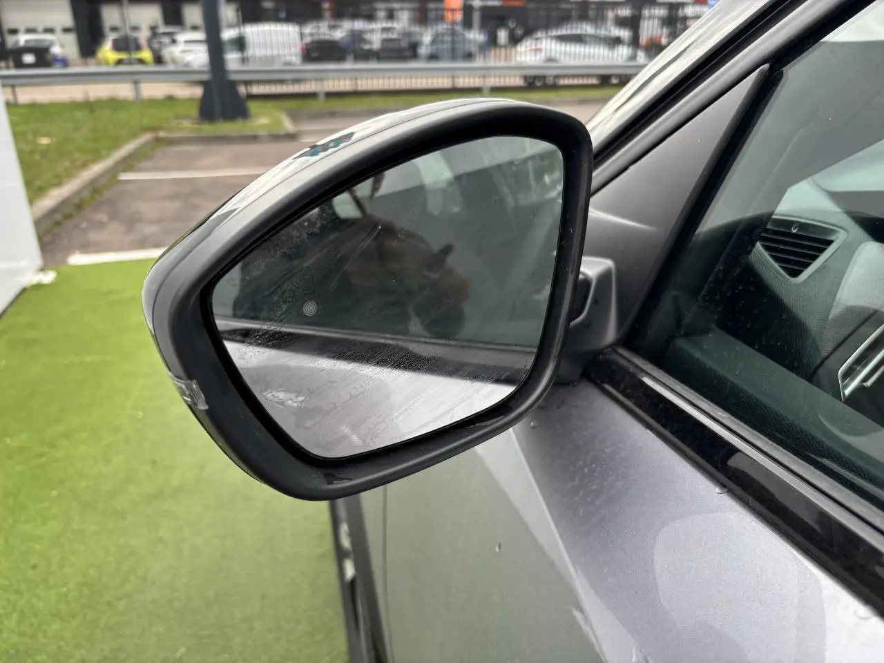 Rétroviseur extérieur côté gauche du Peugeot 2008 gris Artense avec toit noir, vue rapprochée sur la portière avant.