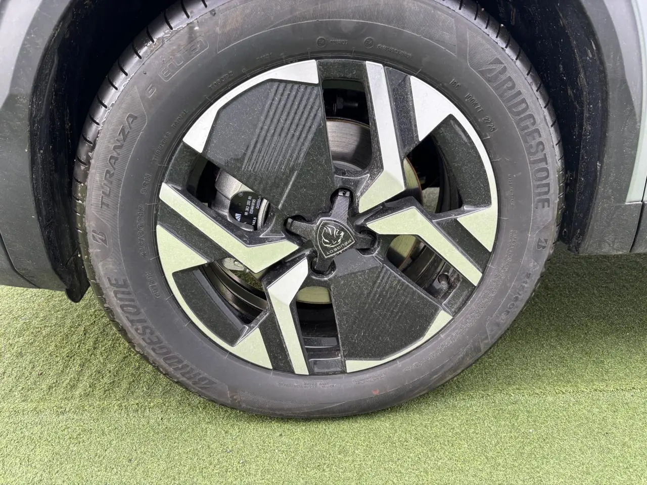 Gros plan sur la jante alliage bi-ton noir et gris du côté gauche d’un Peugeot 2008 gris Artense.