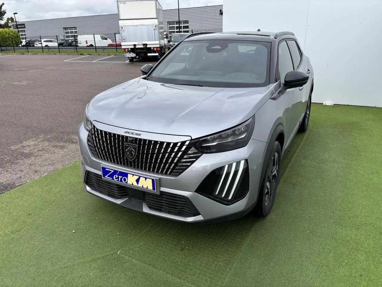 Peugeot 2008 gris Artense toit noir vue 3/4 avant avec calandre verticale et feux LED griffes distinctifs.