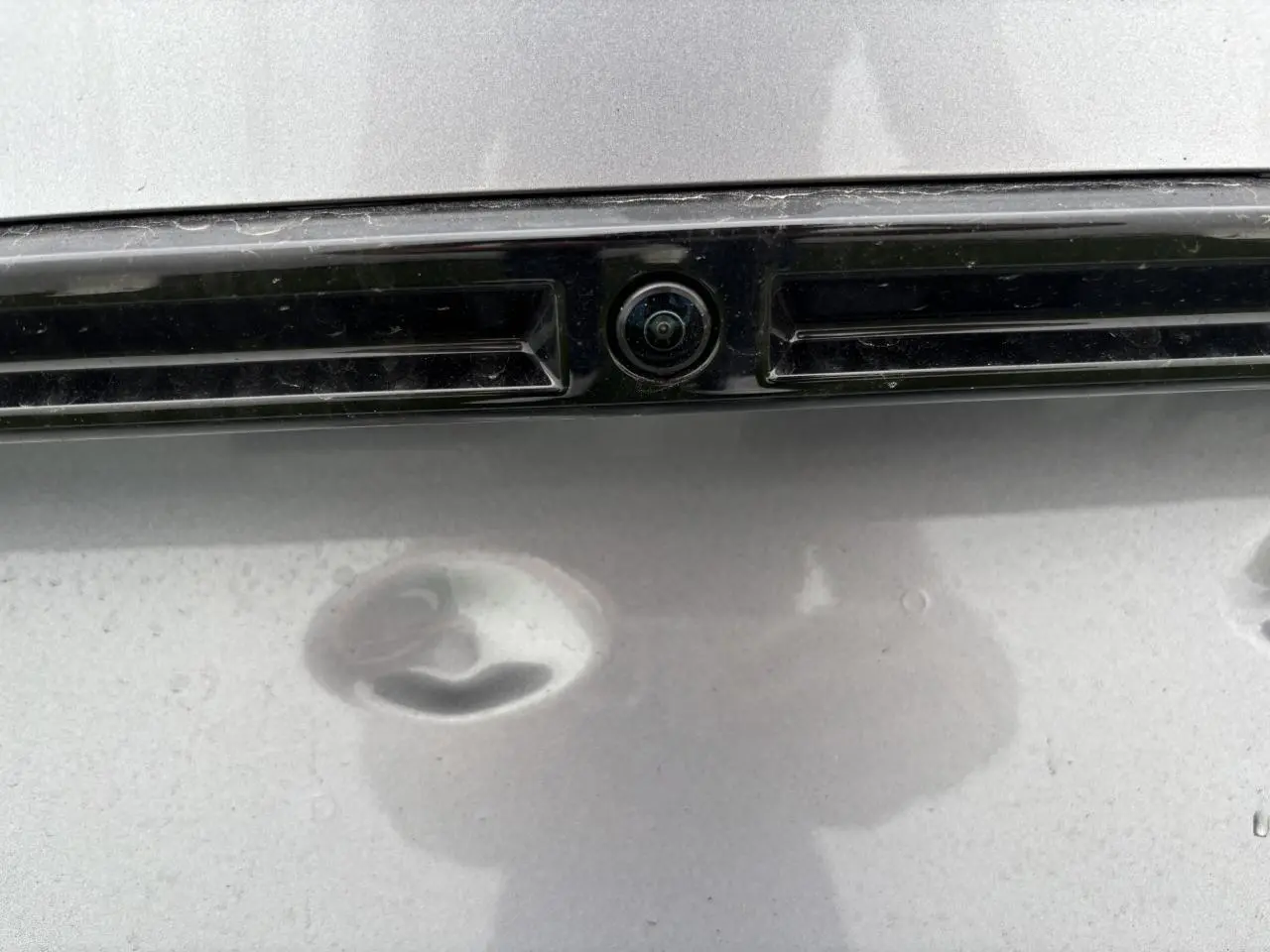 Gros plan sur la caméra 360° arrière intégrée à la plaque d’immatriculation du Peugeot 2008 gris Artense.