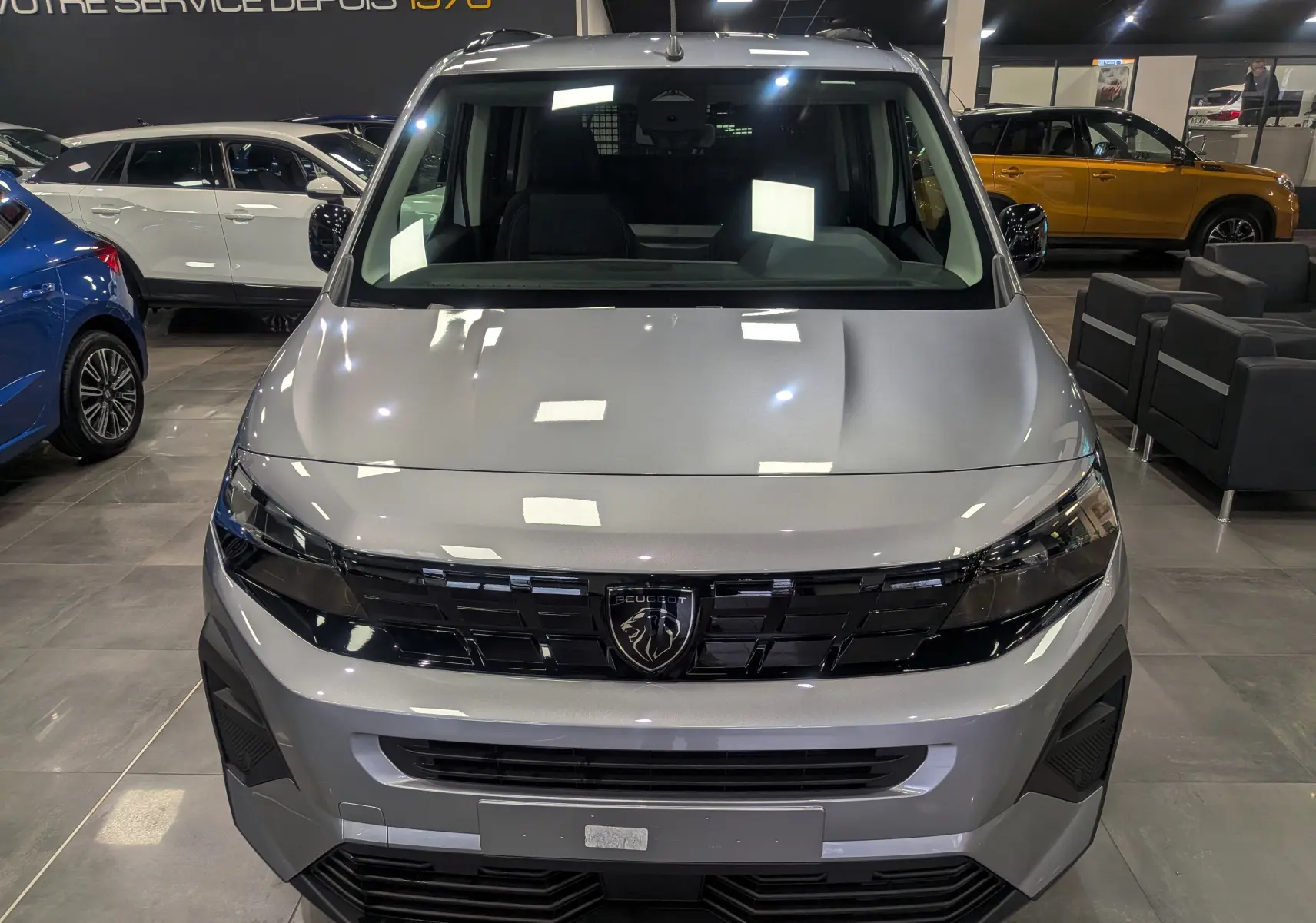 Vue frontale du Peugeot Rifter 2025 gris acier, mettant en valeur la calandre noire avec logo lion central.