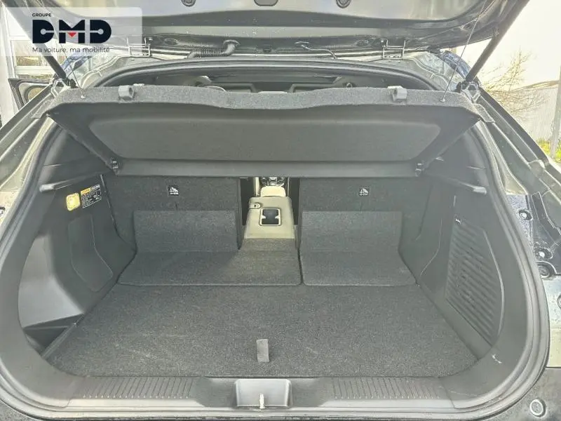 Coffre ouvert vu de l'arrière d'un Suzuki Vitara 2026 vert Land Breeze avec toit noir, banquette rabattue et accoudoir central.