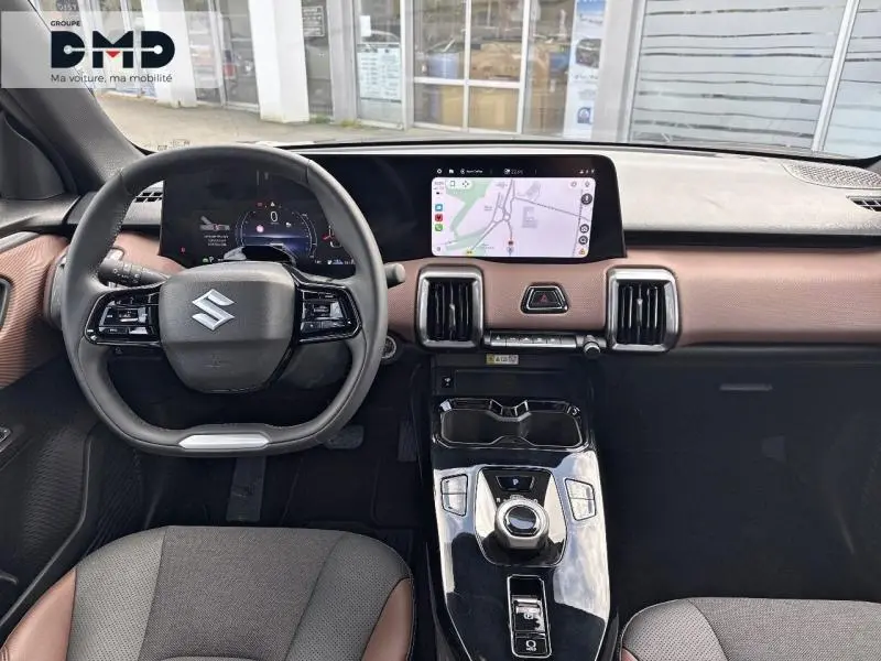 Vue intérieure avant du Suzuki Vitara 2026 avec tableau de bord marron et noir, écran tactile GPS et volant multifonction.