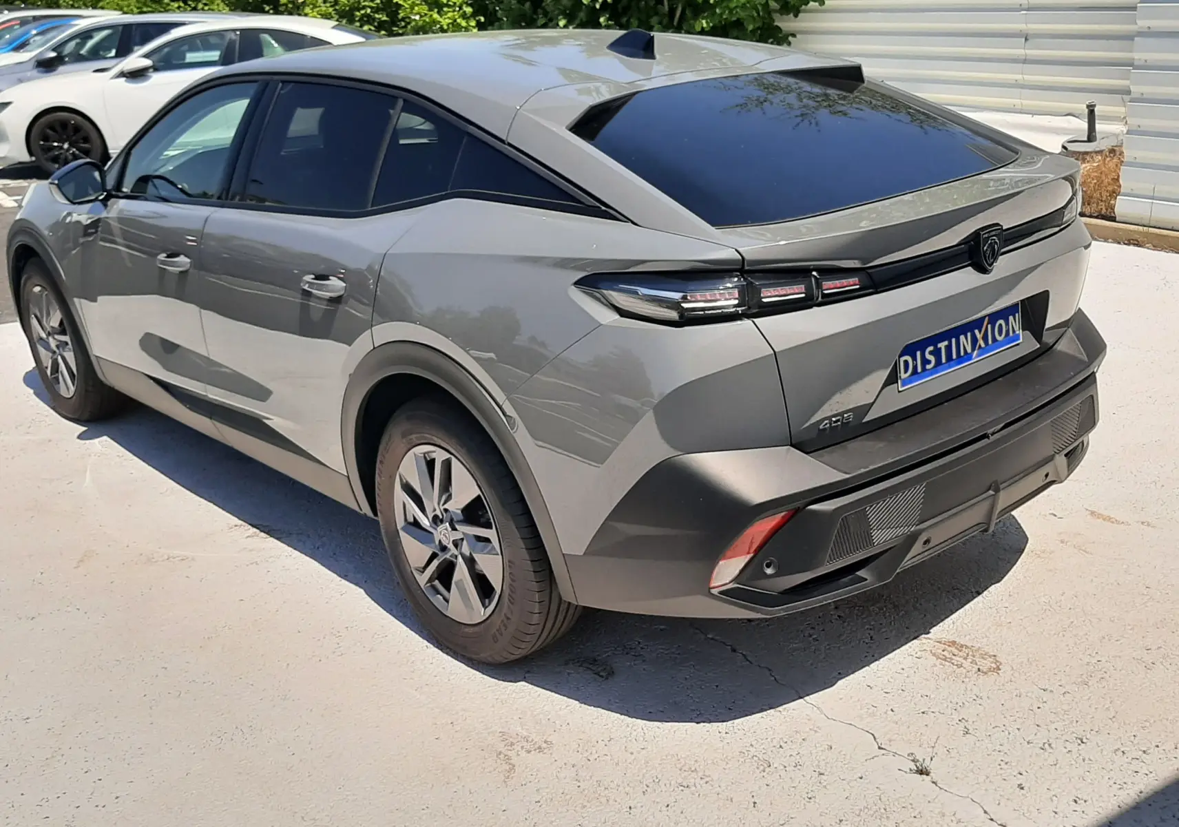Vue 3/4 arrière droite d'une Peugeot 408 hybride gris selenium avec toit noir et feux arrière LED distinctifs.