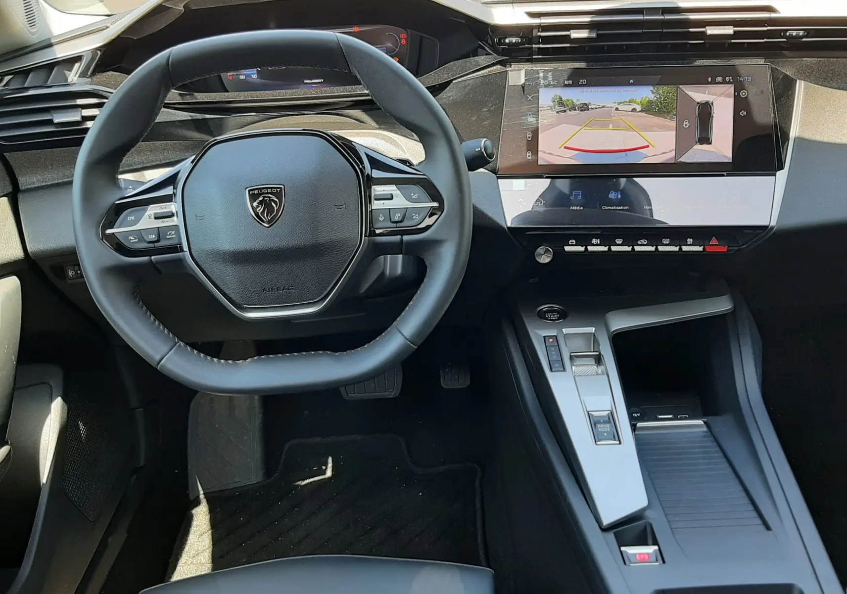 Vue intérieure avant de la Peugeot 408 Hybrid 2024, tableau de bord moderne avec écran tactile affichant la caméra de recul.