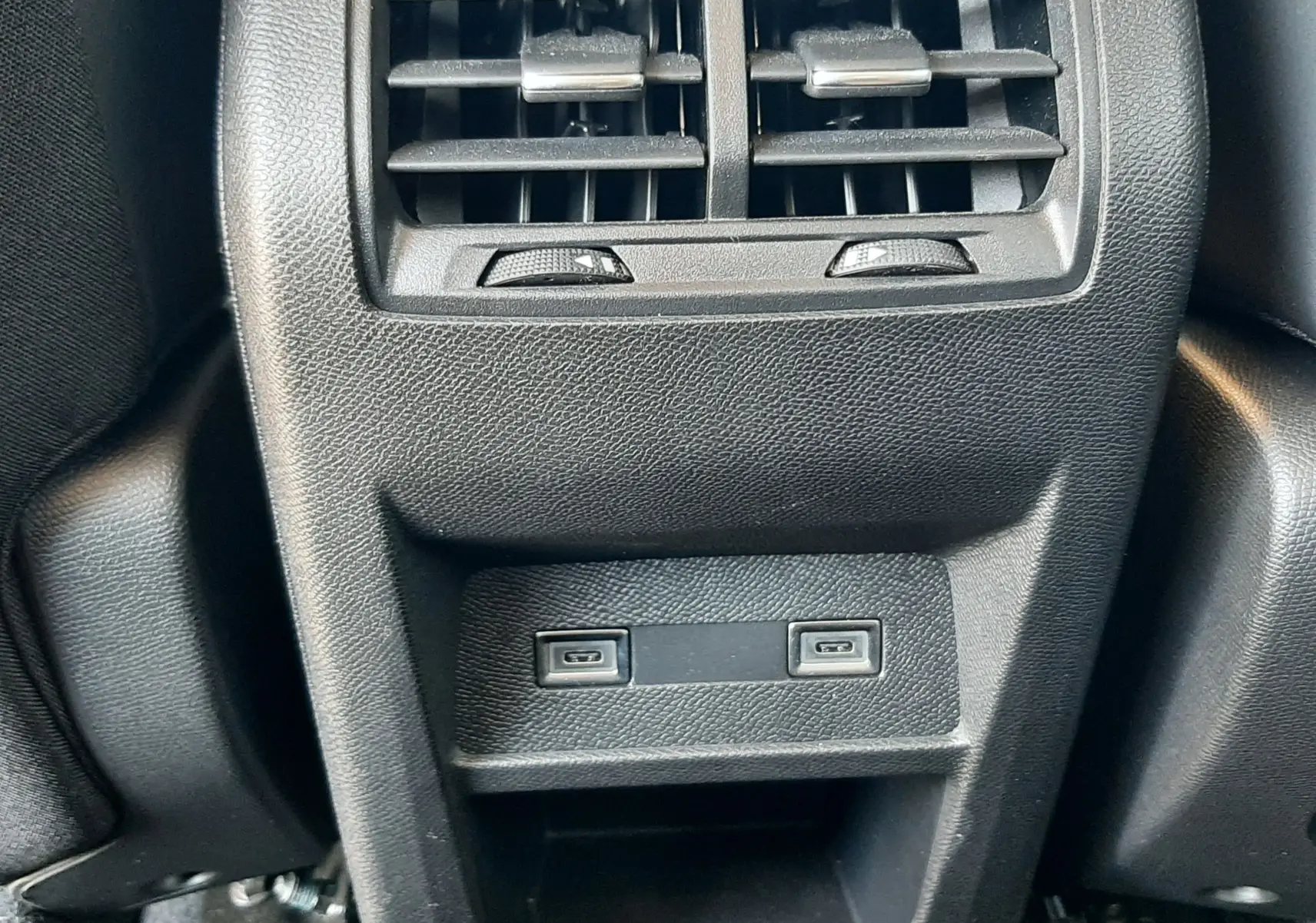 Vue rapprochée des aérateurs arrière et ports USB du Peugeot 408 Hybrid 145ch Allure gris Selenium, intérieur noir.