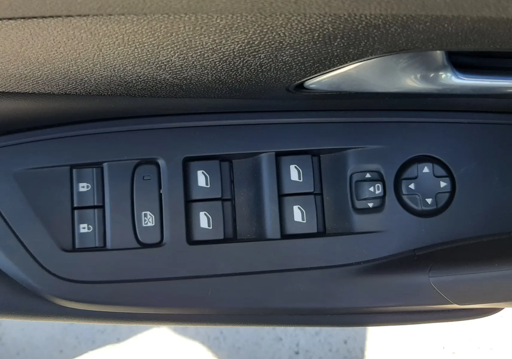 Gros plan sur les commandes de lève-vitres et rétroviseurs côté conducteur d’une Peugeot 408 gris sélénium 2024.