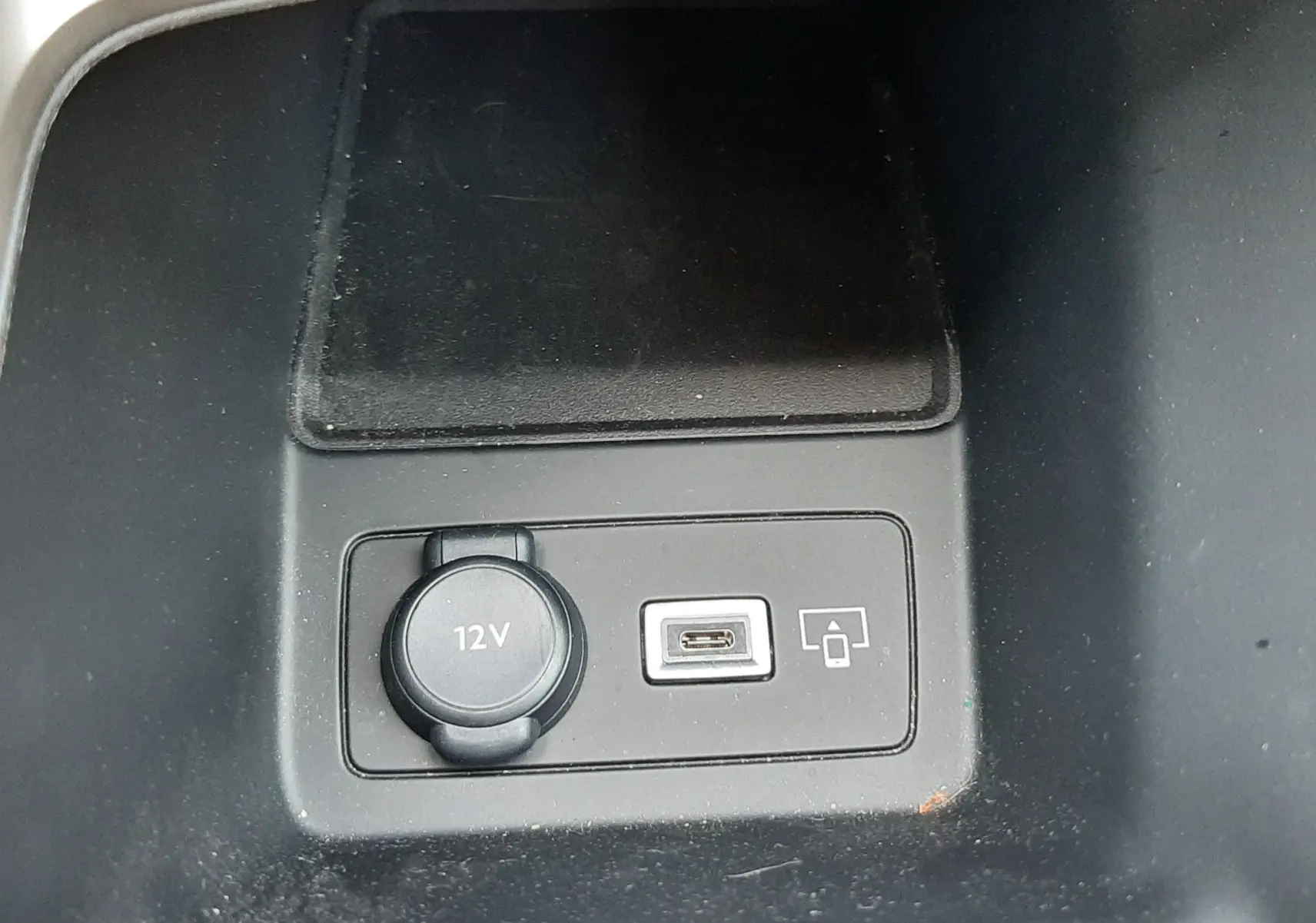 Prise 12V et port USB-C en gros plan sur la console centrale d’une Peugeot 408 gris selenium 2024.