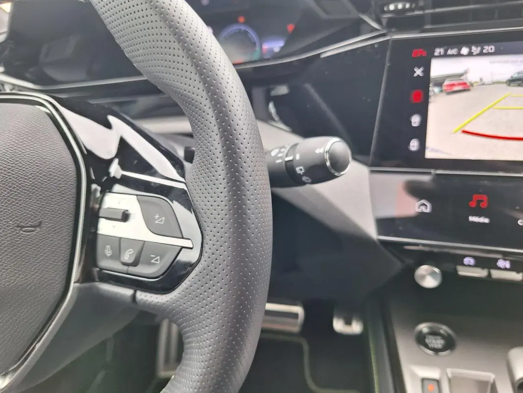 Vue intérieure rapprochée du volant perforé et de l’écran tactile affichant la caméra de recul du Peugeot 308 gris Hybrid 145 e-DCS6 GT.