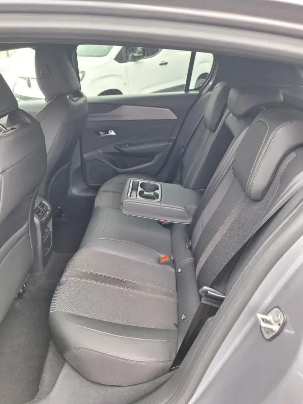 Vue intérieure côté gauche des sièges arrière gris du Peugeot 308 Hybrid 145 e-DCS6 GT avec accoudoir central et porte-gobelets.