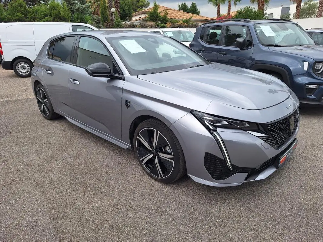 Peugeot 308 Hybrid gris en 3/4 avant droit, avec jantes alliage 18 pouces et signature lumineuse verticale LED.