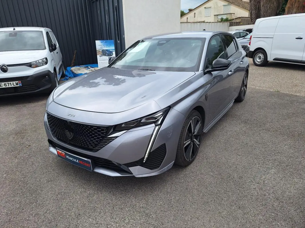 PEUGEOT 308 Hybrid gris en 3/4 avant droit, avec calandre noire et jantes alliage 18 pouces visibles.