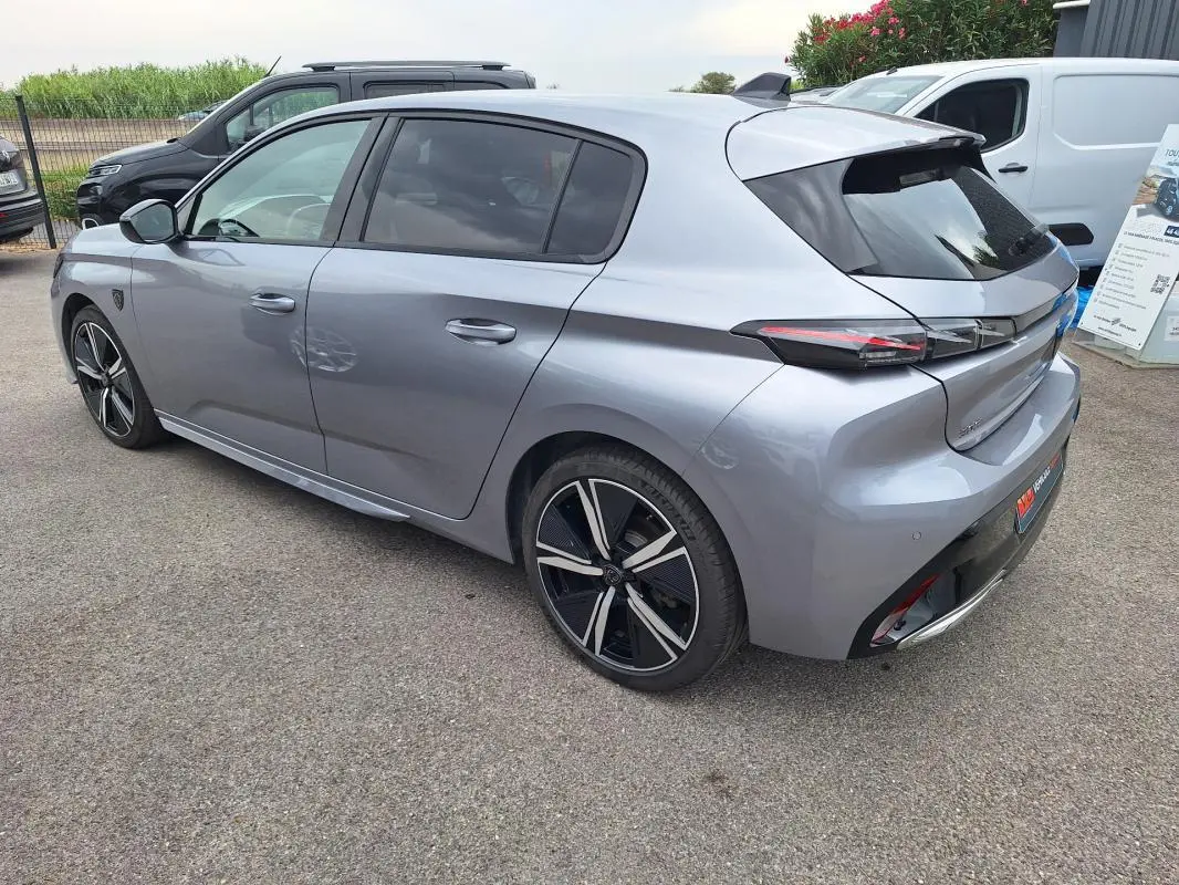 Vue 3/4 arrière droite d'une Peugeot 308 Hybrid 145 e-DCS6 GT gris avec jantes alliage 18 pouces et vitres teintées.