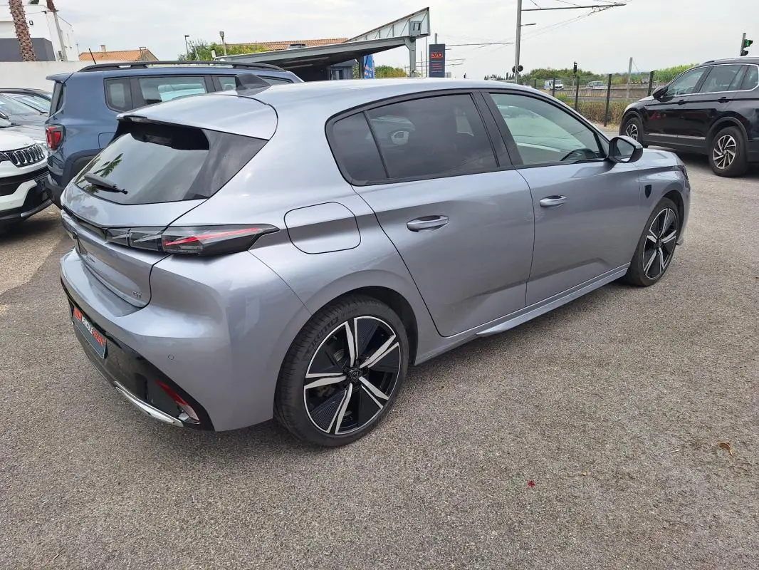 Peugeot 308 Hybrid gris vue 3/4 arrière droit, jantes alliage 18 pouces et vitres teintées visibles.