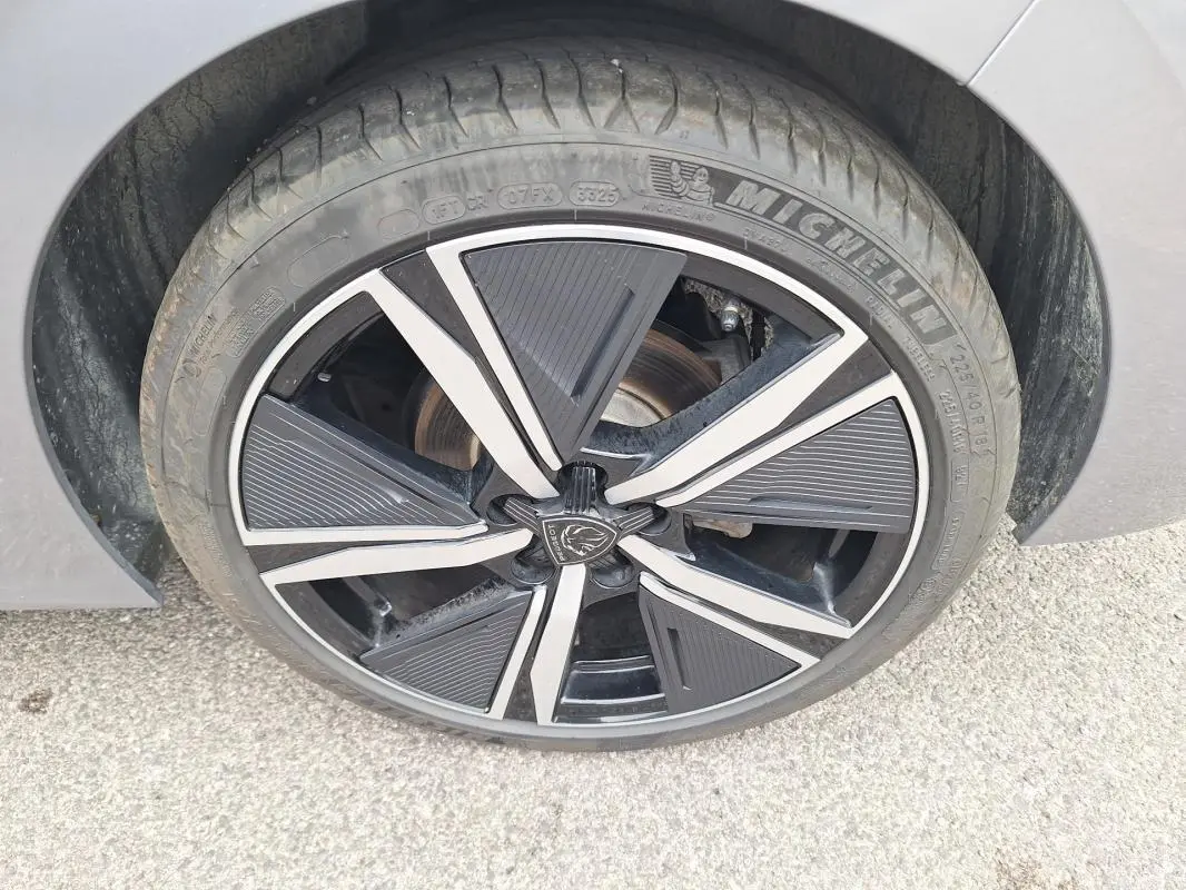Gros plan sur la jante alliage noire et argentée de 18 pouces du Peugeot 308 Hybrid 145 e-DCS6 GT gris, côté droit.
