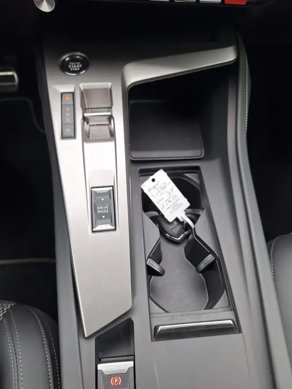 Vue plongeante sur la console centrale grise de la Peugeot 308 Hybrid 145 e-DCS6 GT avec levier de vitesses et porte-gobelets.