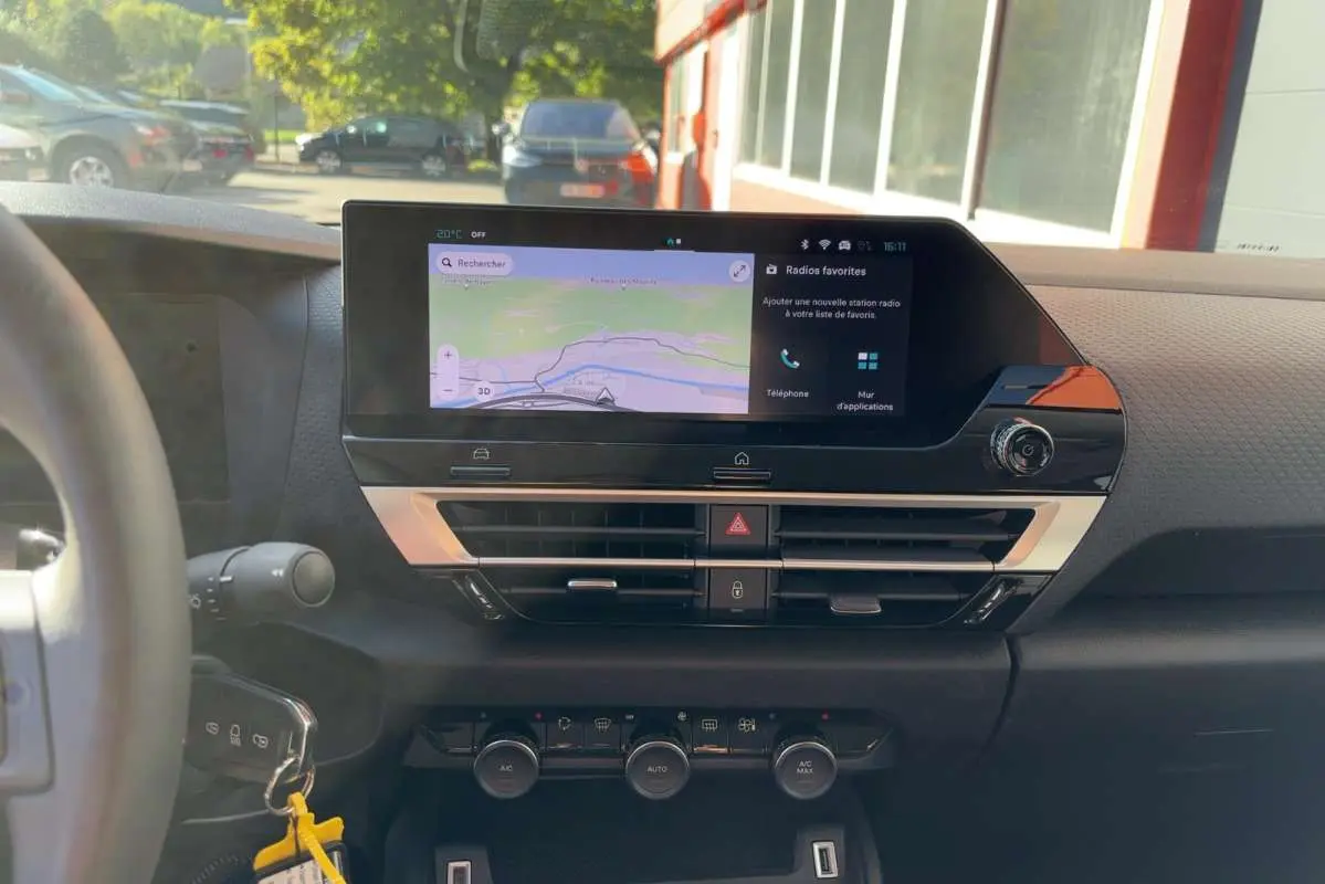 Vue intérieure du tableau de bord de la Citroën C4 hybride 2025, avec écran tactile de navigation et commandes de climatisation.