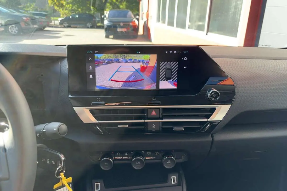 Vue intérieure du tableau de bord de la Citroën C4 hybride 2025 avec écran de caméra de recul et commandes climatisation.